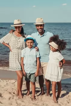Family consisting of husband, wife, and two kids taking photo on the beach during their Caribbean cruise. 